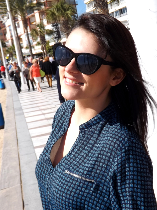 With sunglasses at the beach, wearing black jeans and black shoes