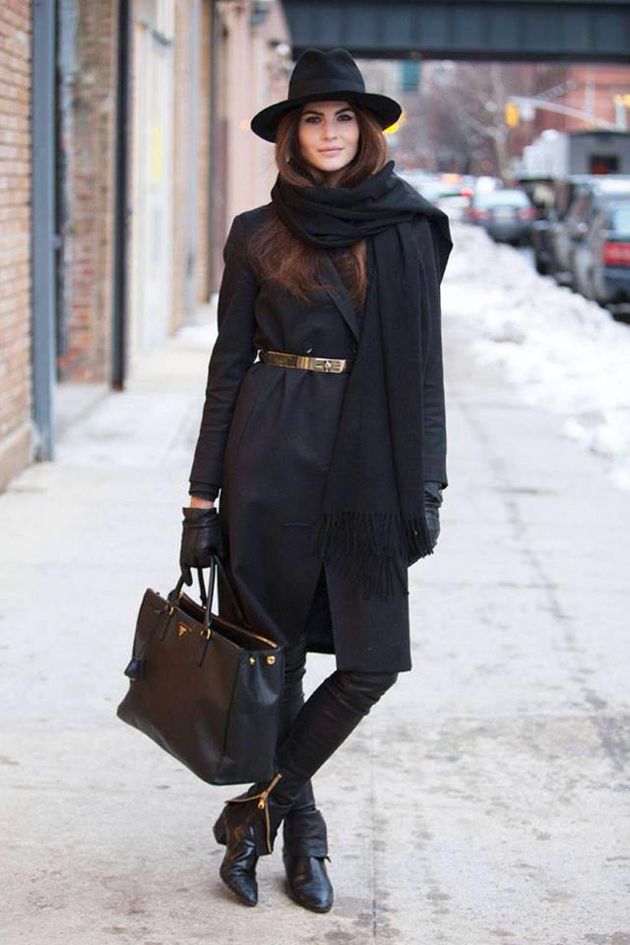 a woman wearing black boots, black pants, black coat and a sexy hat. She looks very pretty 